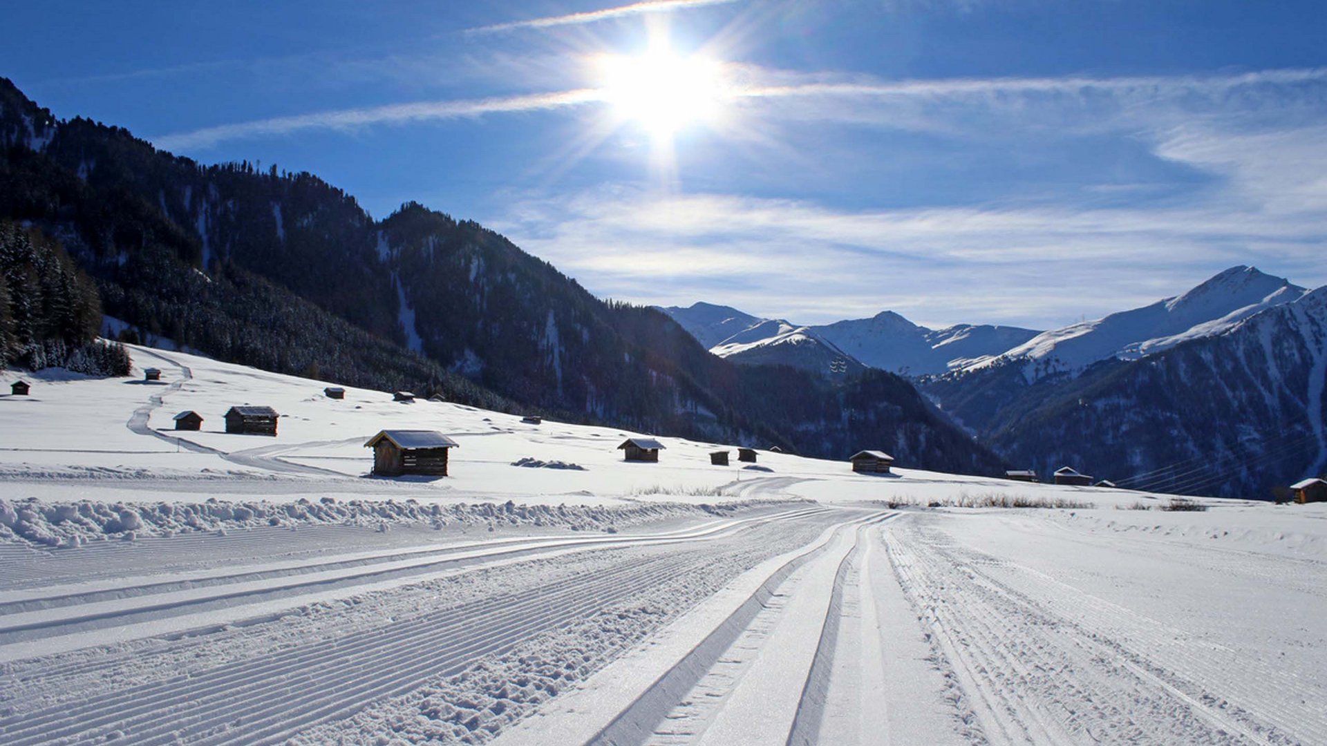 Langlaufen in Tirol: fantastisch! Schneebedeckte Landschaft mit Skispuren und sonnigem Himmel über den Bergen