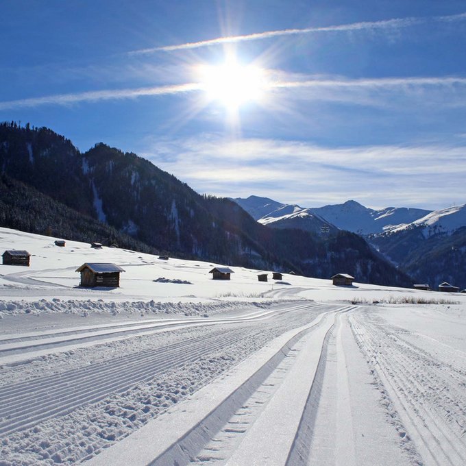 Langlaufen in Tirol: fantastisch! Schneebedeckte Landschaft mit Skispuren und sonnigem Himmel über den Bergen