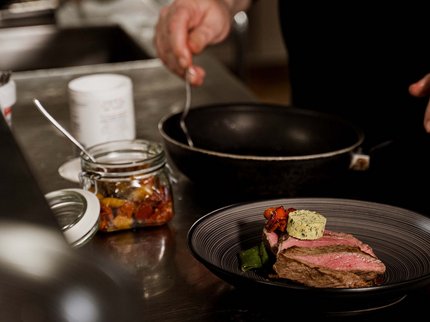 Alpine Kulinarik in Prutz Rindersteak mit Butter und Gemüse auf Teller in Küche angerichtet