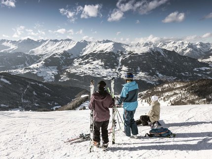 Hotel Post: Ihr Skihotel in Tirol Drei Skifahrer auf verschneitem Berg mit Blick auf Bergkette bei klarem Himmel