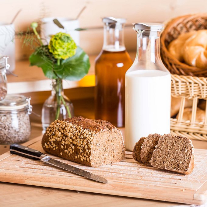 Alpine Kulinarik in Prutz Geschnittenes Vollkornbrot auf Holzbrett mit Milch, Öl und Backwaren im Hintergrund