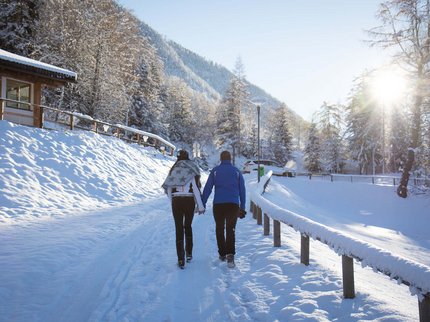 Winterurlaub in Tirol – Skispaß & Entspannung in den Alpen Paar hält Händchen beim Spazierengehen auf verschneitem Weg im Winter