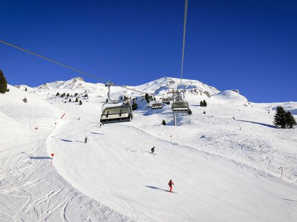 Hotel Post: Ihr Skihotel in Tirol Skilift und Skifahrer auf schneebedecktem Berg unter klarem blauem Himmel