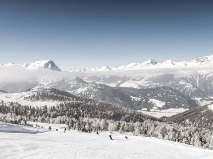 Winterurlaub in Tirol – Skispaß & Entspannung in den Alpen Skifahrer auf verschneiter Piste mit Alpengebirge und bewölktem Himmel im Hintergrund