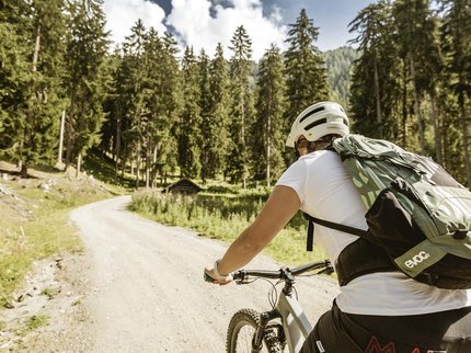 Hotel in Prutz gesucht? Person mit Helm radelt auf Waldweg in bergiger Landschaft