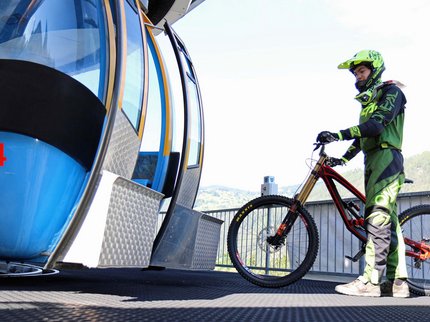 Entdecken Sie im Sommerurlaub die Tiroler Bergseen. Mountainbiker mit Helm neben Seilbahn in Berglandschaft