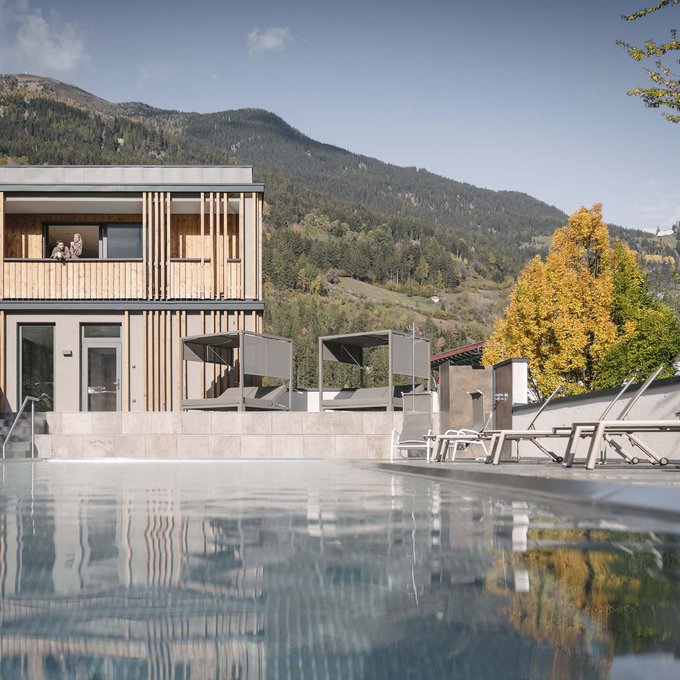 Ihre Unterkunft in Prutz Moderner Holzbau neben einem Pool mit Bergen und Herbstbäumen im Hintergrund