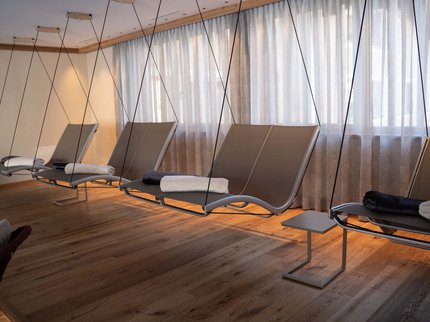 Wellnesshotel in Tirol gesucht? Moderne hängende Liegestühle mit Handtüchern in einem hellen Raum