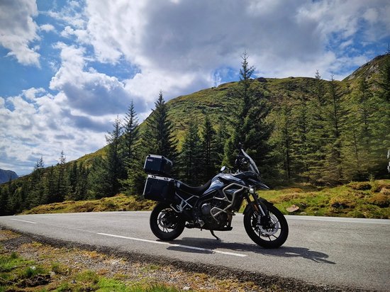 Echtes Kleinod aus dem Tiroler Oberland Motorrad auf Bergstraße mit Tannenbäumen und bewölktem Himmel