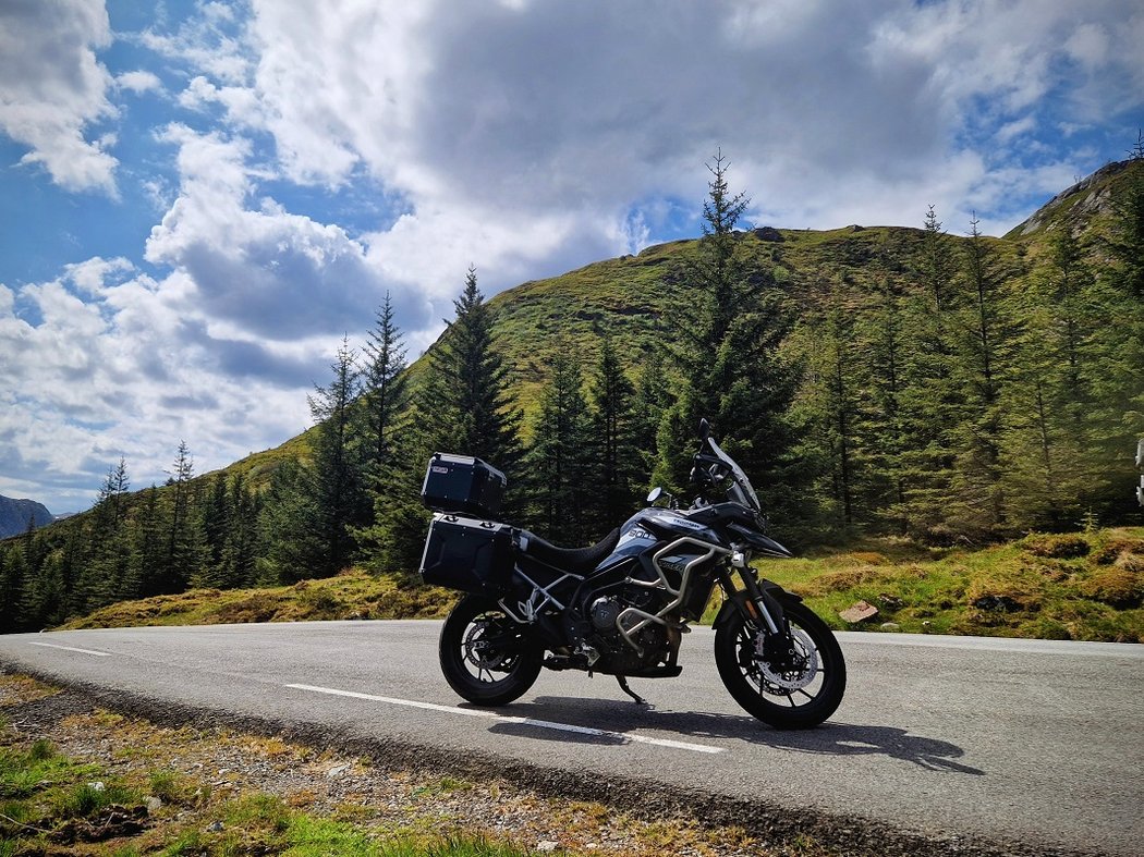 Hier findet jeder Biker seine Traumtour Motorrad auf Bergstraße mit Tannenbäumen und bewölktem Himmel
