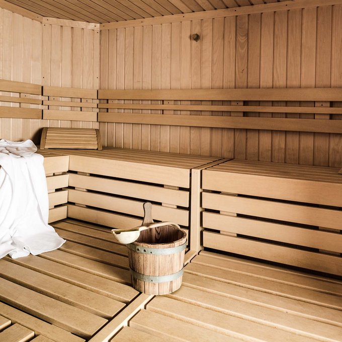Wellnesshotel in Tirol gesucht? Leere Holzsauna mit Handtuch und Eimer mit Kelle auf dem Boden
