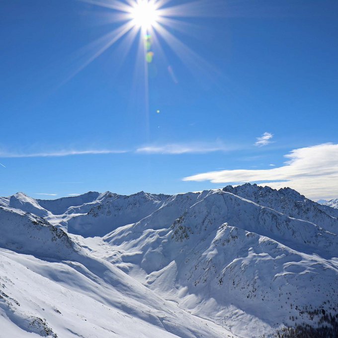 Winterurlaub in Tirol – Skispaß & Entspannung in den Alpen Sonniger Tag mit schneebedeckten Bergen unter klarem blauem Himmel