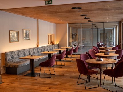 Alpine Kulinarik in Prutz Gemütlicher Cafébereich mit Holztischen und roten Stühlen in warmer Atmosphäre