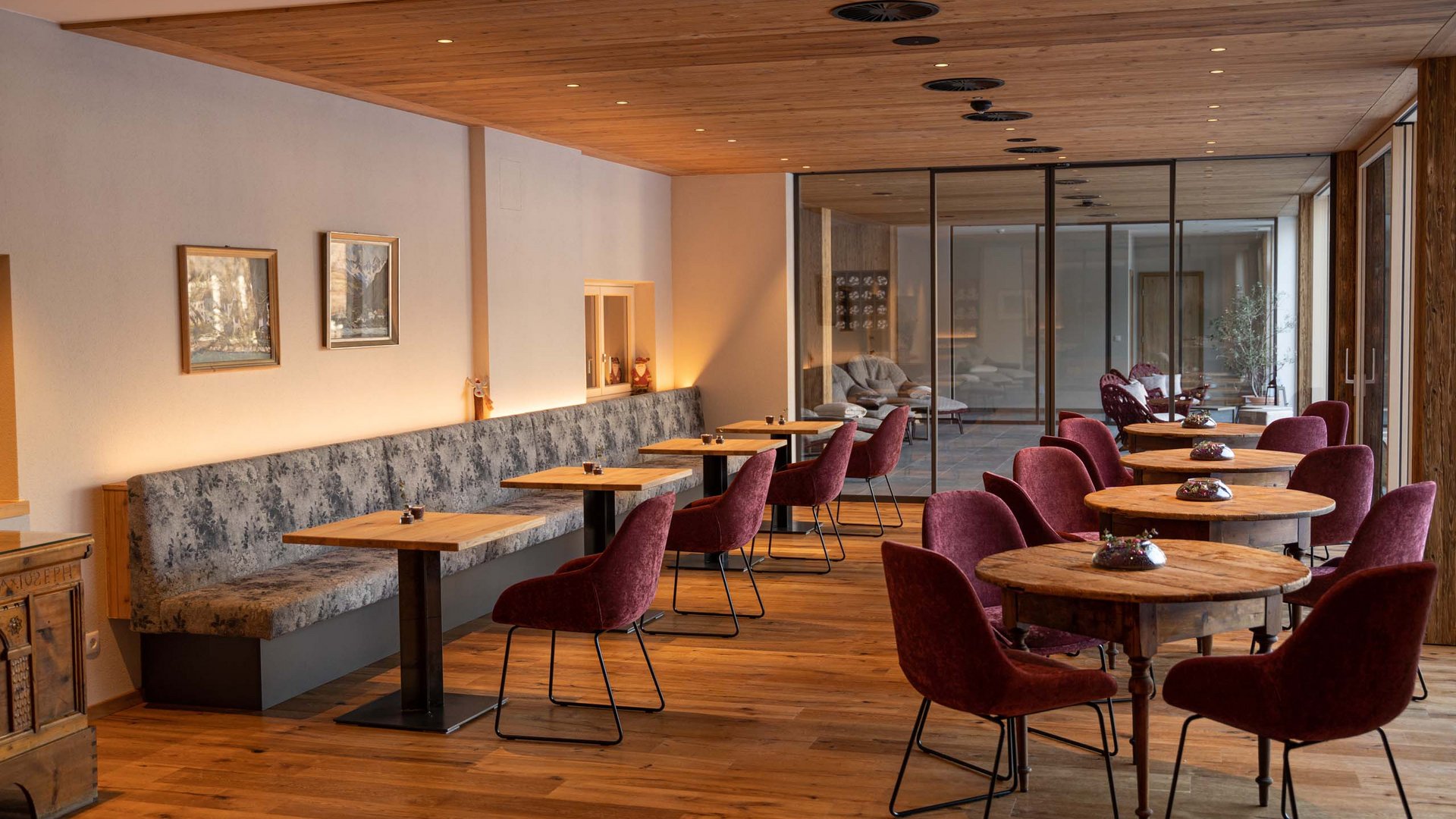 Hotel in Prutz gesucht? Gemütlicher Cafébereich mit Holztischen und roten Stühlen in warmer Atmosphäre