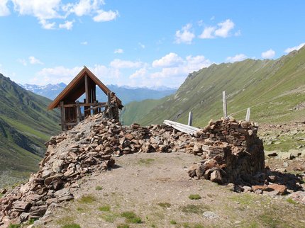 Entdecken Sie im Sommerurlaub die Tiroler Bergseen. Ruine einer Steinhütte in den grünen Bergen unter blauem Himmel