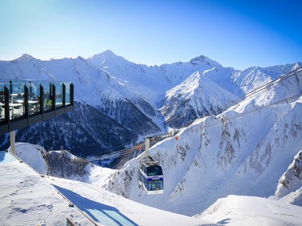 Hotel Post: Ihr Skihotel in Tirol Seilbahn in verschneiten Alpenbergen bei klarem Himmel mit Aussichtsterrasse