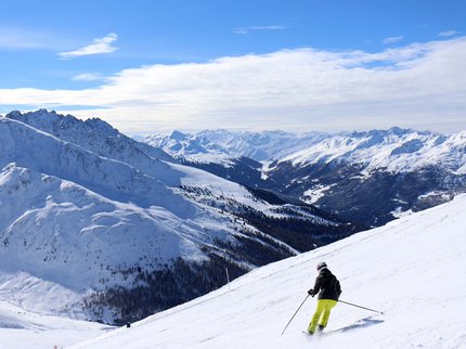 Hotel Post: Ihr Skihotel in Tirol Skifahrer fährt bergab auf schneebedecktem Hang mit Alpenpanorama
