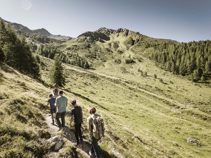 Hotel in Prutz gesucht? Gruppe von Wanderern auf einem Bergweg in einer sonnigen alpinen Landschaft