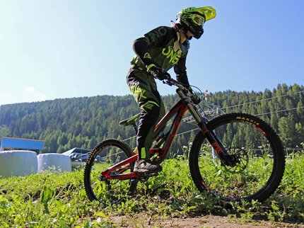 Entdecken Sie im Sommerurlaub die Tiroler Bergseen. Mountainbiker mit Helm fährt bergauf auf einem Trail im Wald