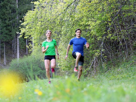 Echtes Kleinod aus dem Tiroler Oberland Frau und Mann beim Joggen im Wald an einem sonnigen Frühlingstag