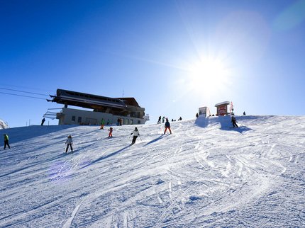 Hotel Post: Ihr Skihotel in Tirol Skifahrer auf einer sonnenbeschienenen Piste bei einem Berglift