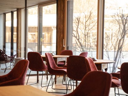 Alpine Kulinarik in Prutz Leerer heller Speiseraum mit roten Stühlen und Holztischen