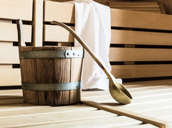 Echtes Kleinod aus dem Tiroler Oberland Holzeimer und Kelle in einer Sauna mit einem weißen Handtuch