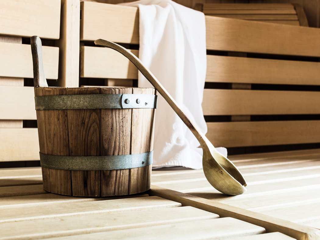 Eintauchen in Wärme und Ruhe – die Saunawelt im Hotel Post in Prutz Holzeimer und Kelle in einer Sauna mit einem weißen Handtuch
