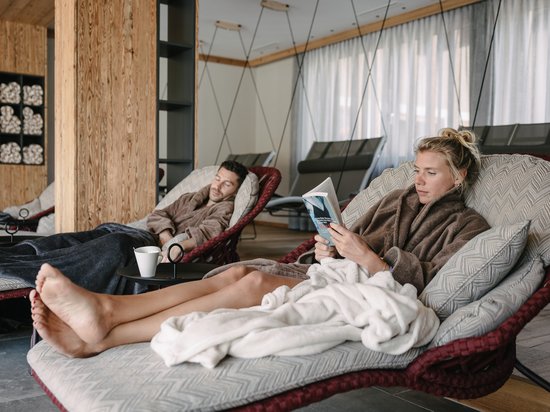 Echtes Kleinod aus dem Tiroler Oberland Zwei Personen in Bademänteln entspannen auf Liegestühlen in einem Spa-Bereich