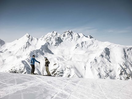 Ihr Hotel in unmittelbarer Nähe von Serfaus-Fiss-Ladis Zwei Skifahrer auf einem schneebedeckten Berg mit schneebedeckten Gipfeln im Hintergrund