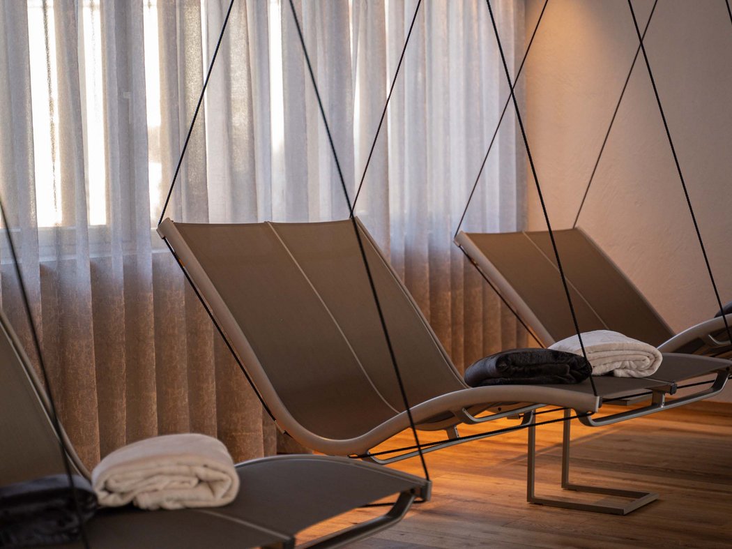 Take a break and rejuvenate. Three hanging lounge chairs with towels by a window with sheer curtains