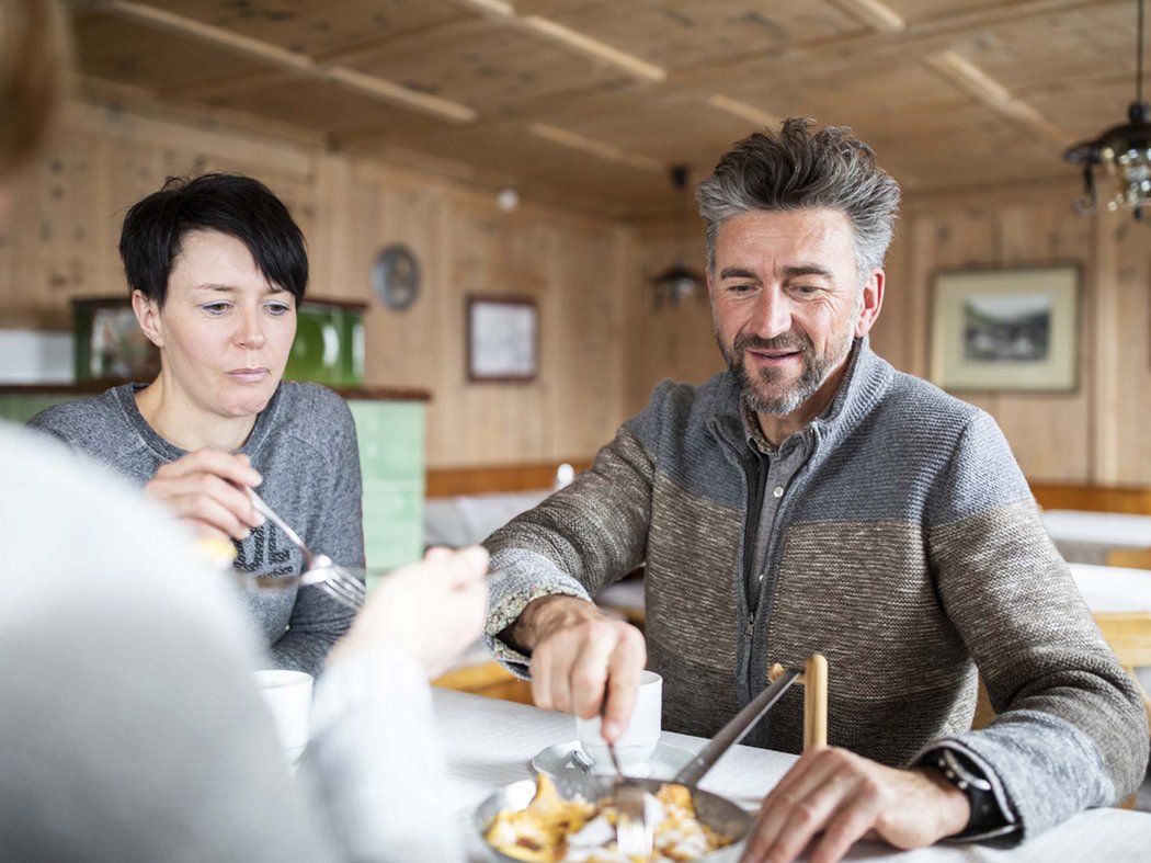 Ski and enjoy Three adults eating together in a cozy wooden cabin