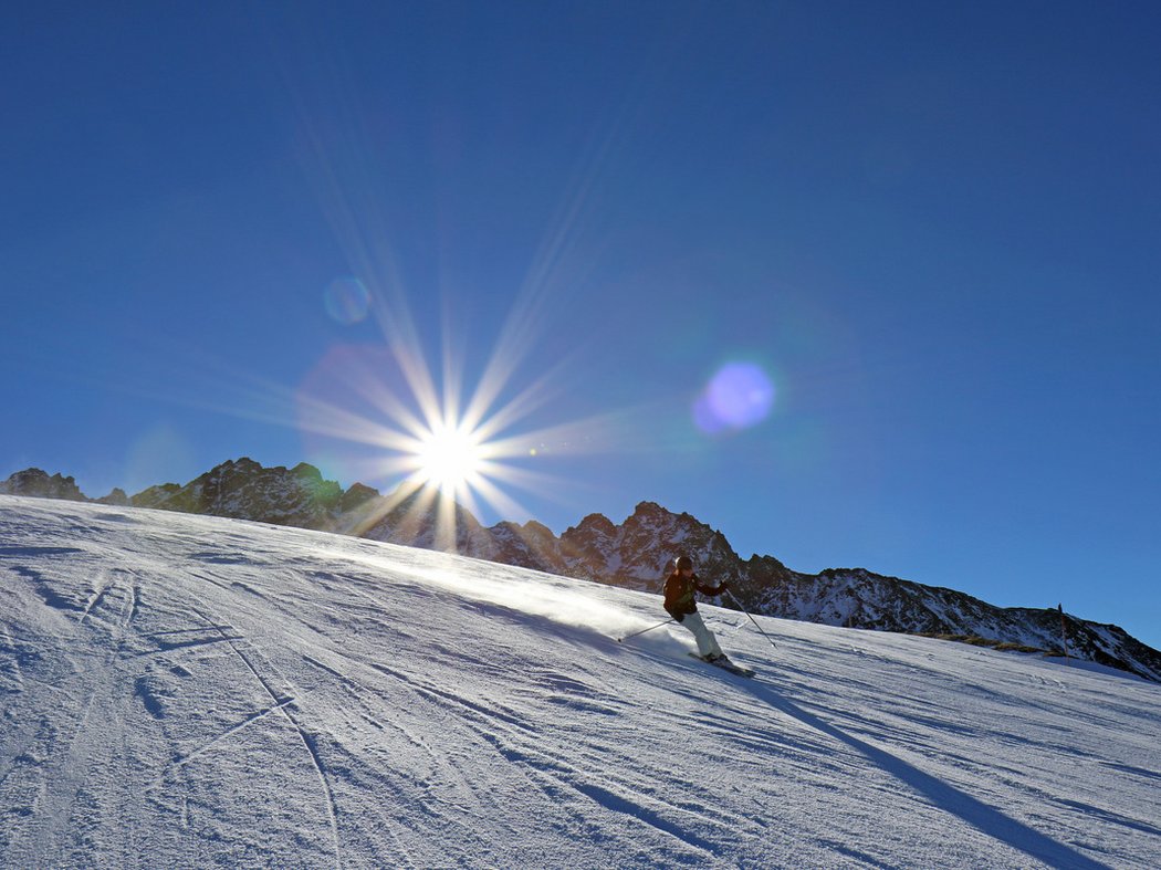 My guide to happiness Skier descending a snowy mountain slope under bright sunlight
